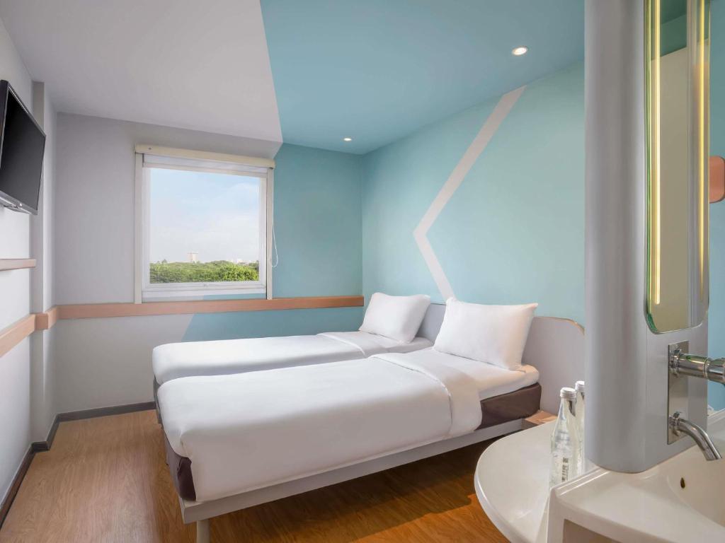 a room with a bed and a sink and a window at Ibis Budget Jakarta Airport in Tangerang