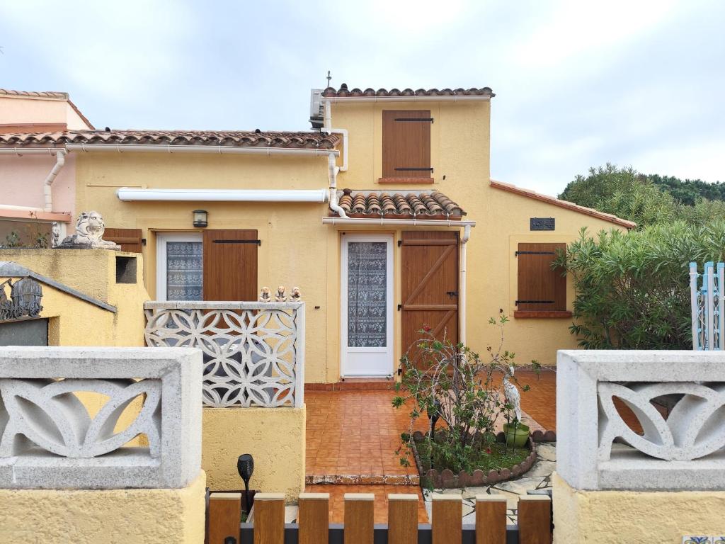 a yellow house with a white door and a fence at Chez David in La Celle-sous-Gouzon