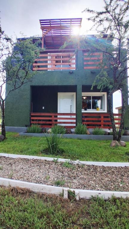 a green building with a bench in front of it at Cabaña Ali in Villa Rumipal