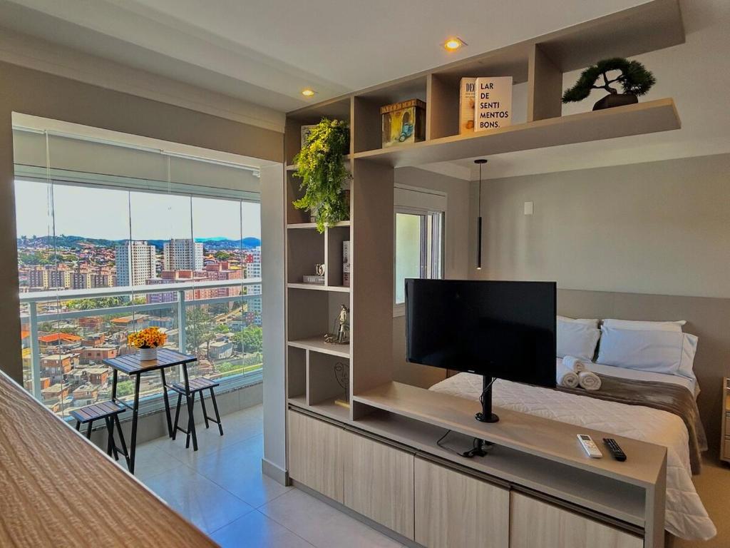 a bedroom with a flat screen tv on a wall at Lindo Studio No Coração da Cidade e Prox ao Aeroporto in Guarulhos