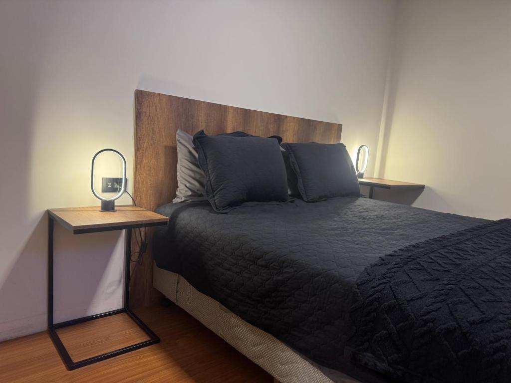 Schlafzimmer mit einem schwarzen Bett und einem Kopfteil aus Holz in der Unterkunft Superb Loft Park Front in Cochabamba