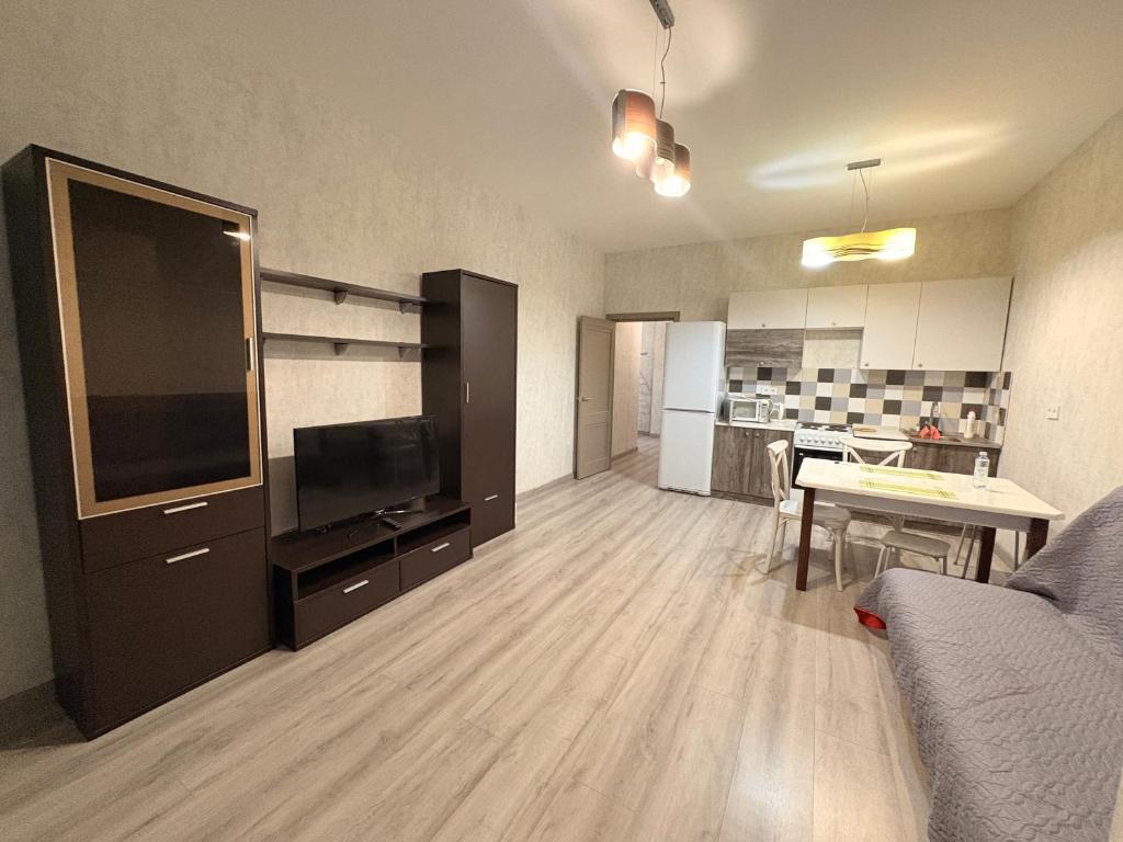 Apple city في Prigorodnyy: غرفة معيشة بها أريكة وتلفزيون وطاولة