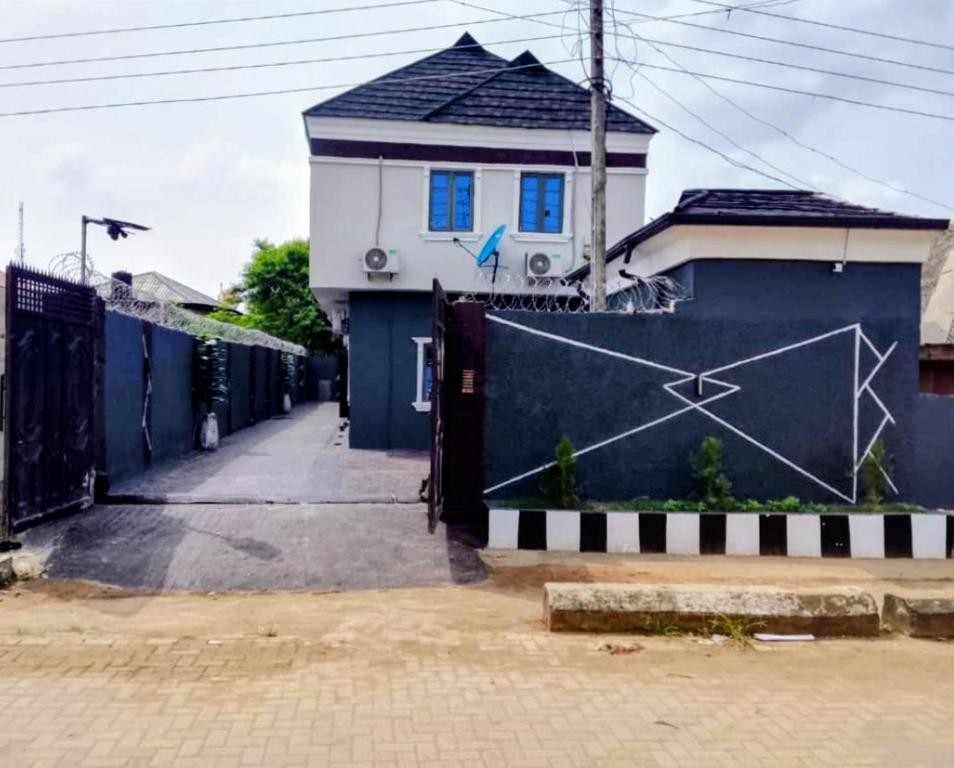 AlimoshoにあるKunbiz Apartmentsの家の前に青いフェンスがある家