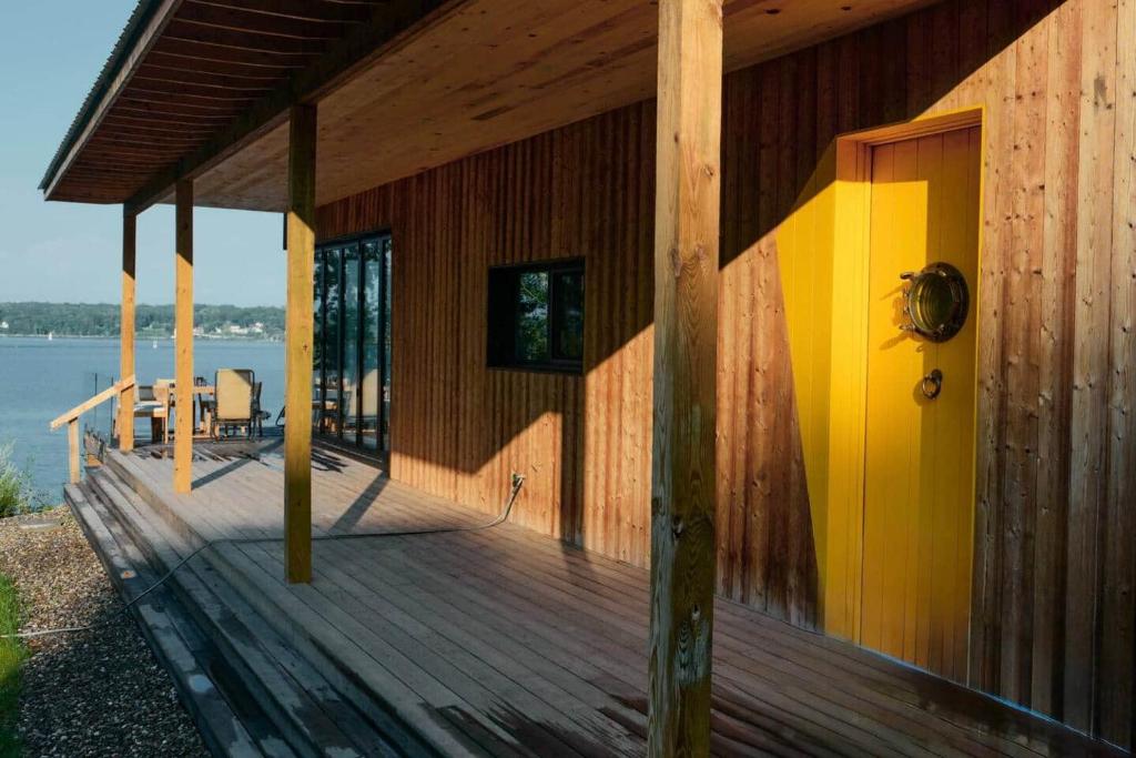 a wooden house with a yellow door on a deck at Shatemuc, a magical getaway on the Hudson River in Kingston