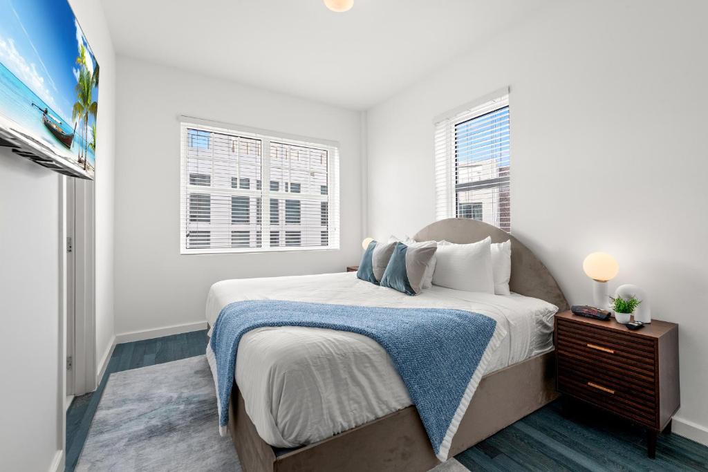 a white bedroom with a bed and two windows at Bluebird Suites at The Apex Miami in Miami Beach