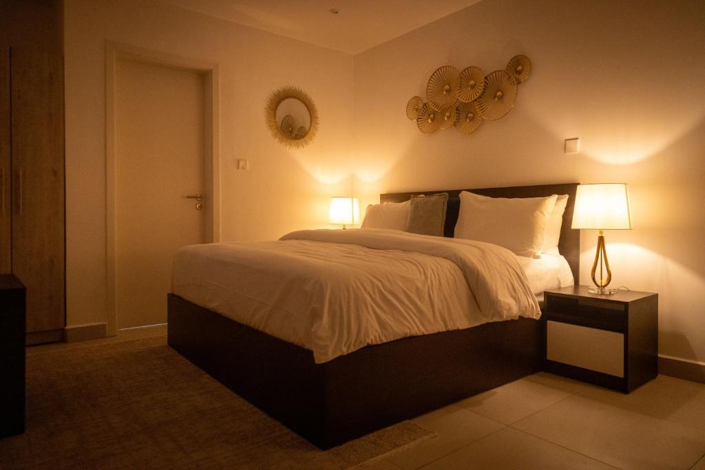 een slaapkamer met een bed met 2 lampen en een spiegel bij Urban Nook, The Bantree in Accra