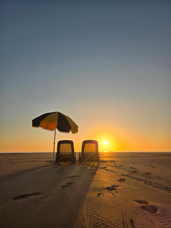 due sedie e un ombrellone in spiaggia al tramonto di Dar Mogador Sun near Taghazout - Surf, Sea, colorful village a Taghazout