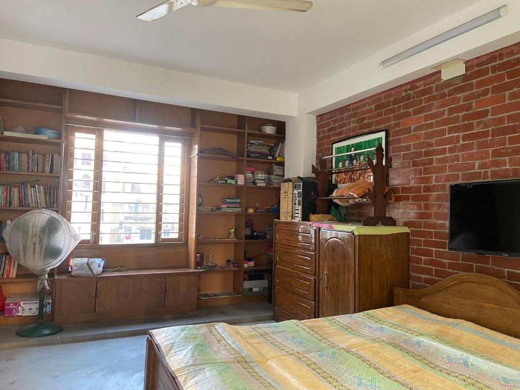 a bedroom with a bed and a brick wall at Rooftop Shantiniketon in Dhaka