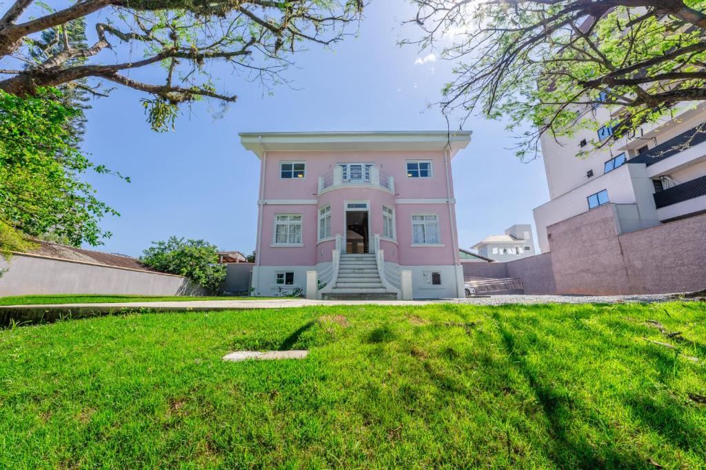 Pousada Encanto da Vila في بلوميناو: منزل وردي مع حديقة أمامه