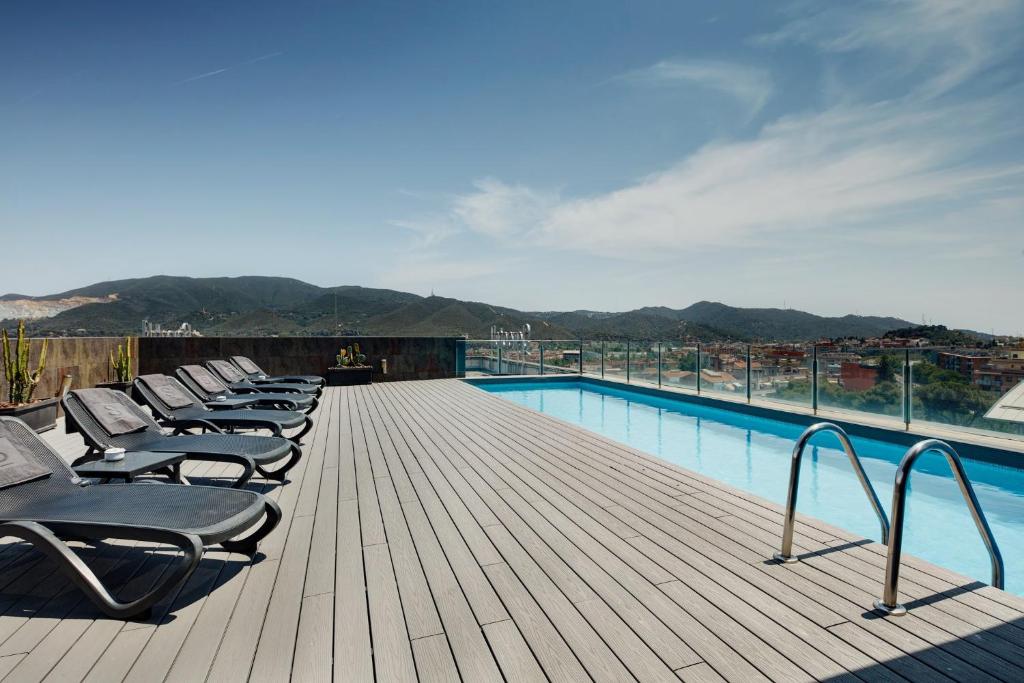 a row of chaise lounges on a deck next to a pool at Sercotel Ciutat de Montcada in Montcada i Reixac