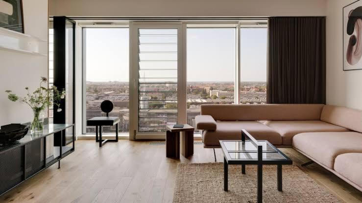 Una sala de estar con un sofá, mesas y ventanas. en Blueyes, en La Marsa