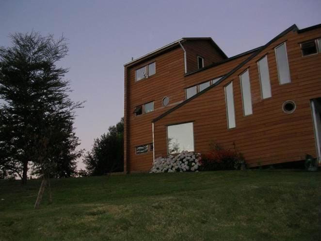un gran edificio de ladrillo en lo alto de un campo verde en Preciosa casa rural, Llau llao,Castro, Chiloé, en Castro