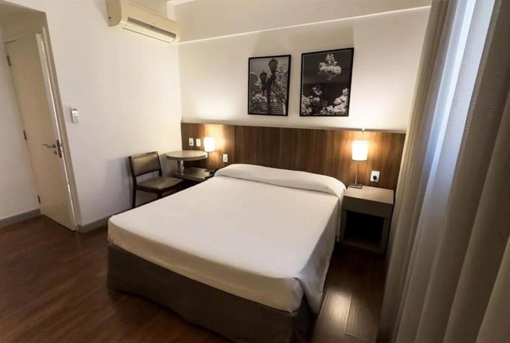 Una habitación de hotel con una cama y un escritorio y una cama. en Hotel Vivenzo Savassi Belo Horizonte, en Belo Horizonte