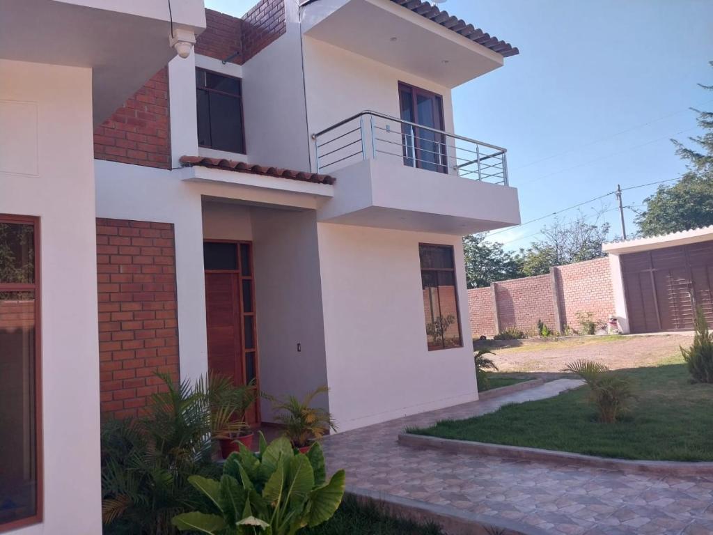 uma casa branca com uma varanda e um quintal em La Retama Houstime em Ayacucho