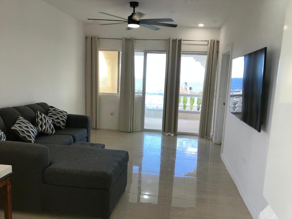 een woonkamer met een bank en een plafondventilator bij So Suite, Negril with seaview in Negril