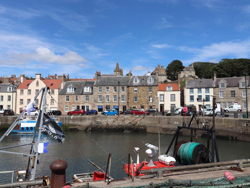 a boat is docked in a river with buildings at Hay Loft in Anstruther