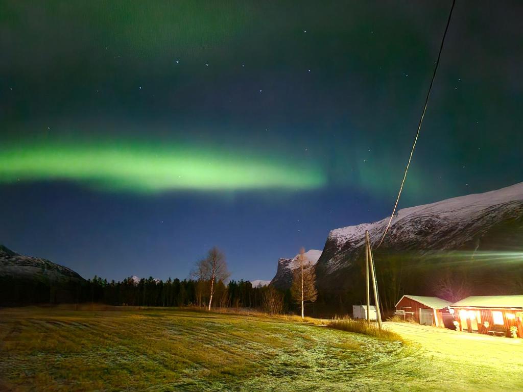 Tørfoss Gård, Hytte utleie, Campingvogn og bobil plasser في Potka: شفق في السماء فوق حقل مع منزل