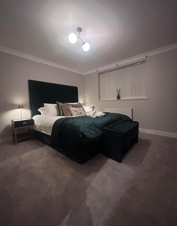 a bedroom with a large bed with a green blanket at Tarn House Apartment South Yorksire in Barnsley