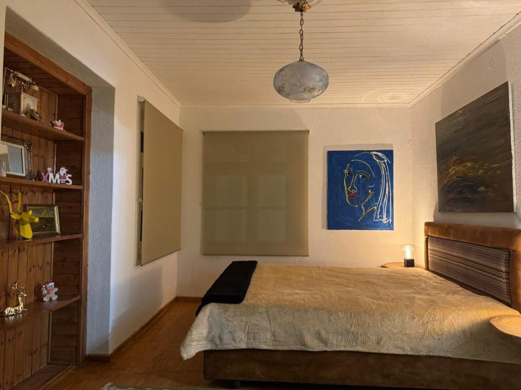 1 dormitorio con 1 cama y una pintura azul en la pared en MZ Maison de la Place, en Eptalofos