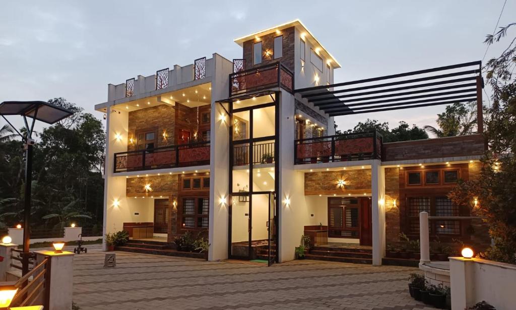 une grande maison éclairée la nuit dans l'établissement Riverbank Gardens, à Mananthavady