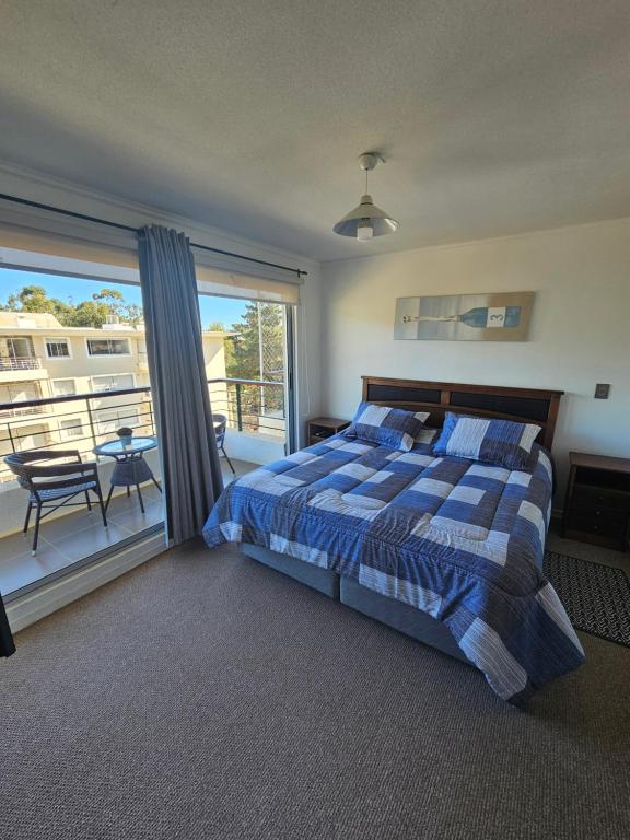 um quarto com uma cama e uma varanda com uma mesa em Parque Mar Depto em El Tabo