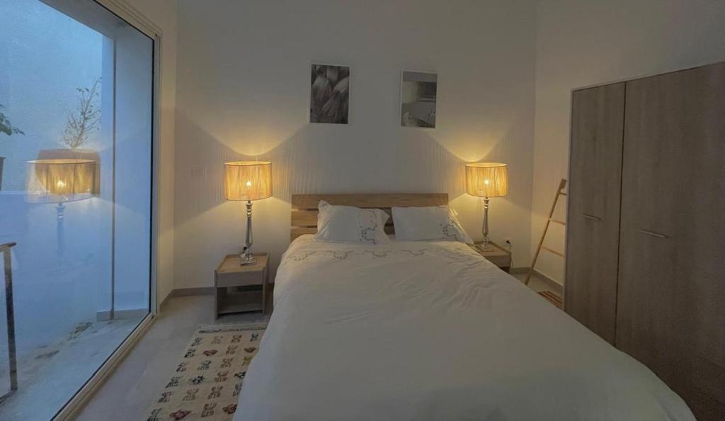 La perle de la marsa في المرسى: غرفة نوم بها سرير أبيض كبير مع مصباحين