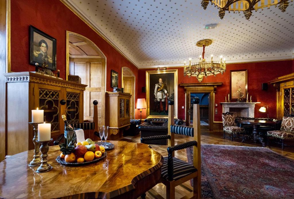Wood-paneled grand lounge with round wooden table, fruit bowl, candlesticks and chandelier, formal elegant mood