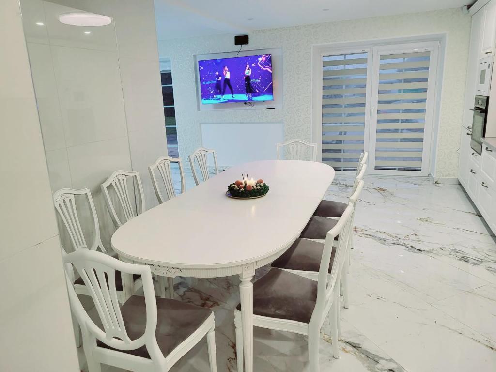 A&G SoDYBA LIUXAPARTAMENT في بلونج: غرفة طعام بيضاء مع طاولة وكراسي بيضاء