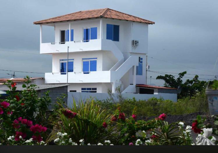 a white house with blue windows and flowers at Bluefootedboobies in Puerto Villamil