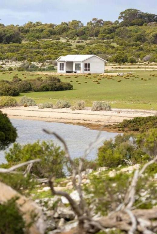 a white house in the middle of a field at Pelican Lagoon Retreat in Pelican Lagoon