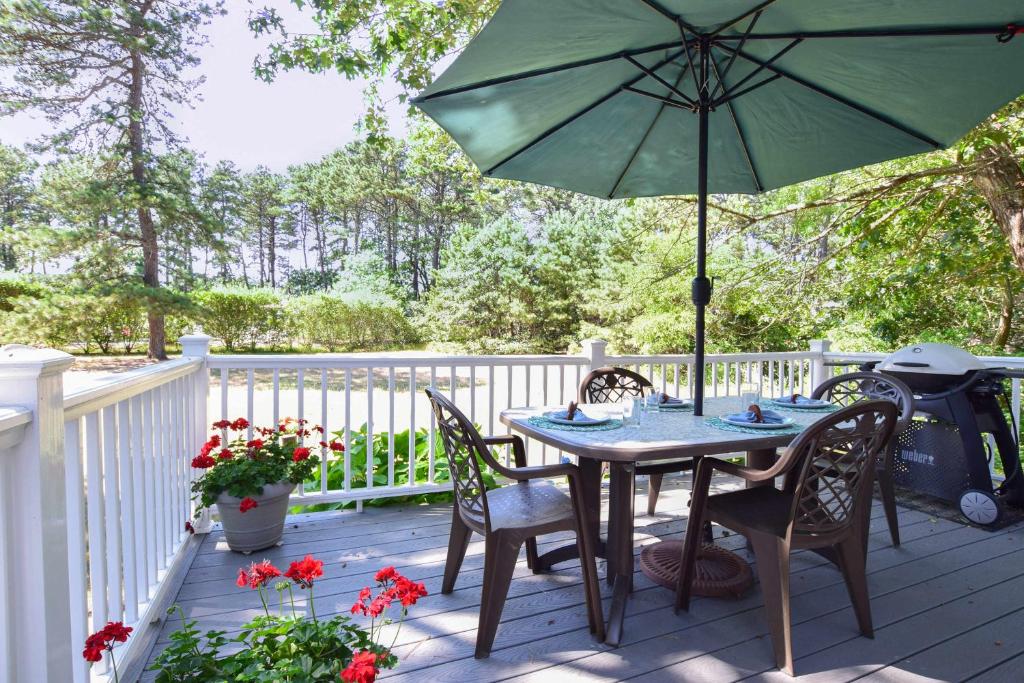 een tafel met stoelen en een parasol op een terras bij Private Association Pool Great Location in Wellfleet
