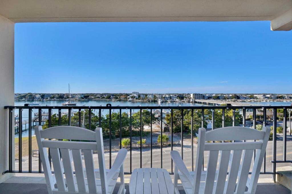 two white chairs on a balcony with a view of the ocean at Summer Sands - 401 by Sea Scape Properties in Wrightsville Beach