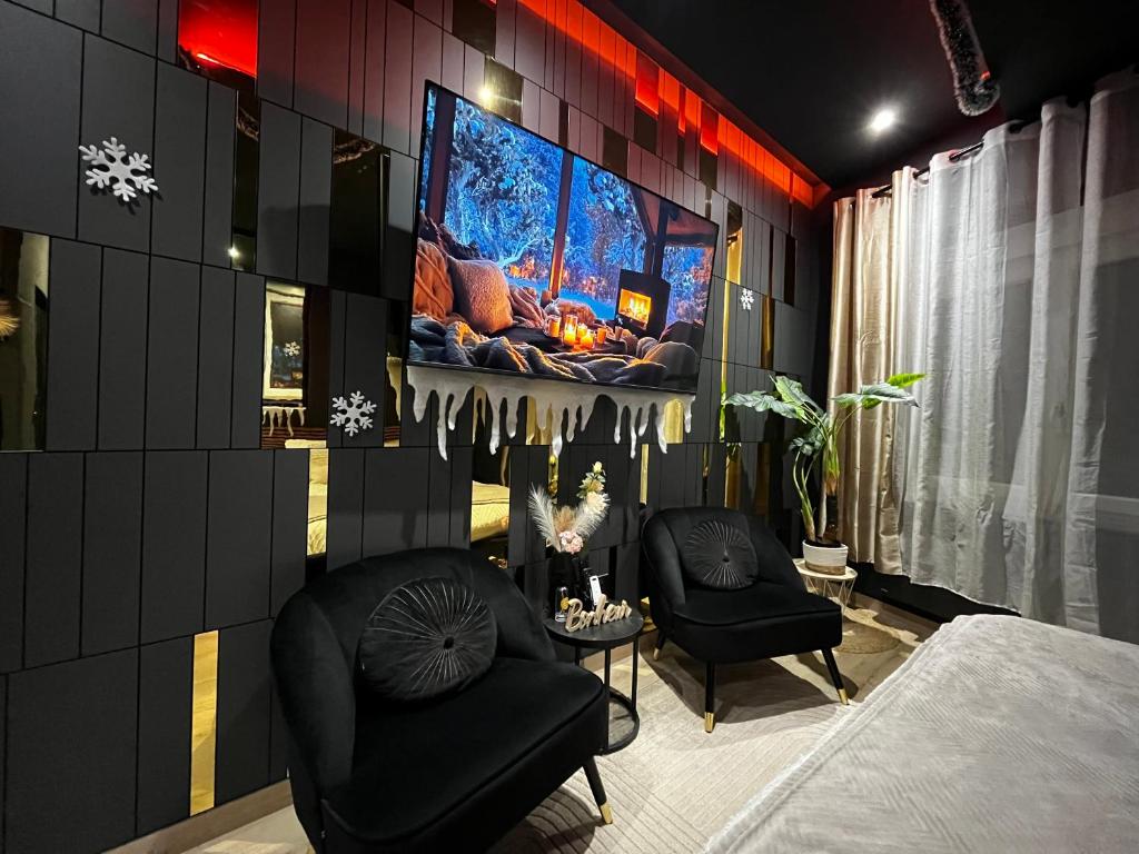 Una habitación con dos sillas y un televisor en una pared. en L'élégance - Charme - Jacuzzi - -Secret- Parking, en Sarrebourg