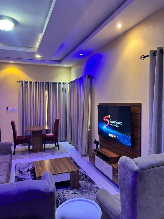 Una sala de estar con televisión, mesa y sillas. en The Private Pearl Apartment, en Ikeja