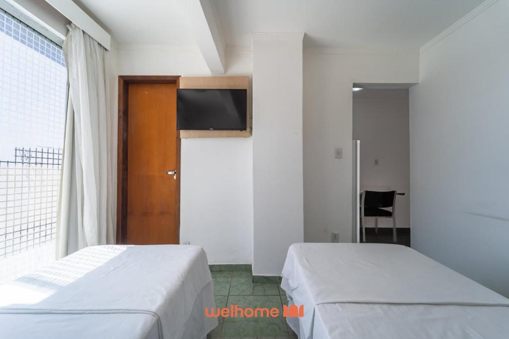 twee bedden in een kamer met een tv aan de muur bij Apartamento em Macae Proximo a Praia do Farol in Imbetiba