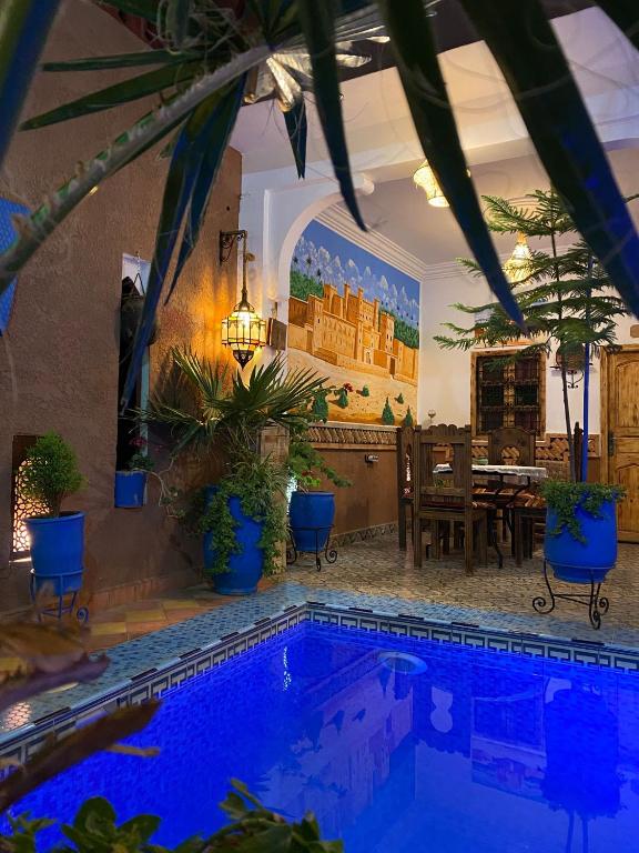 a house with a swimming pool with a table and chairs at Hôtel Bia Besta in Boumalne Dades