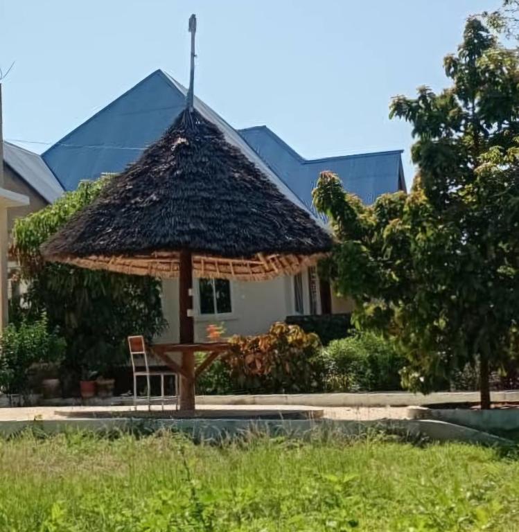 a table with a straw umbrella in front of a house at Kijani House in Banda Kuu