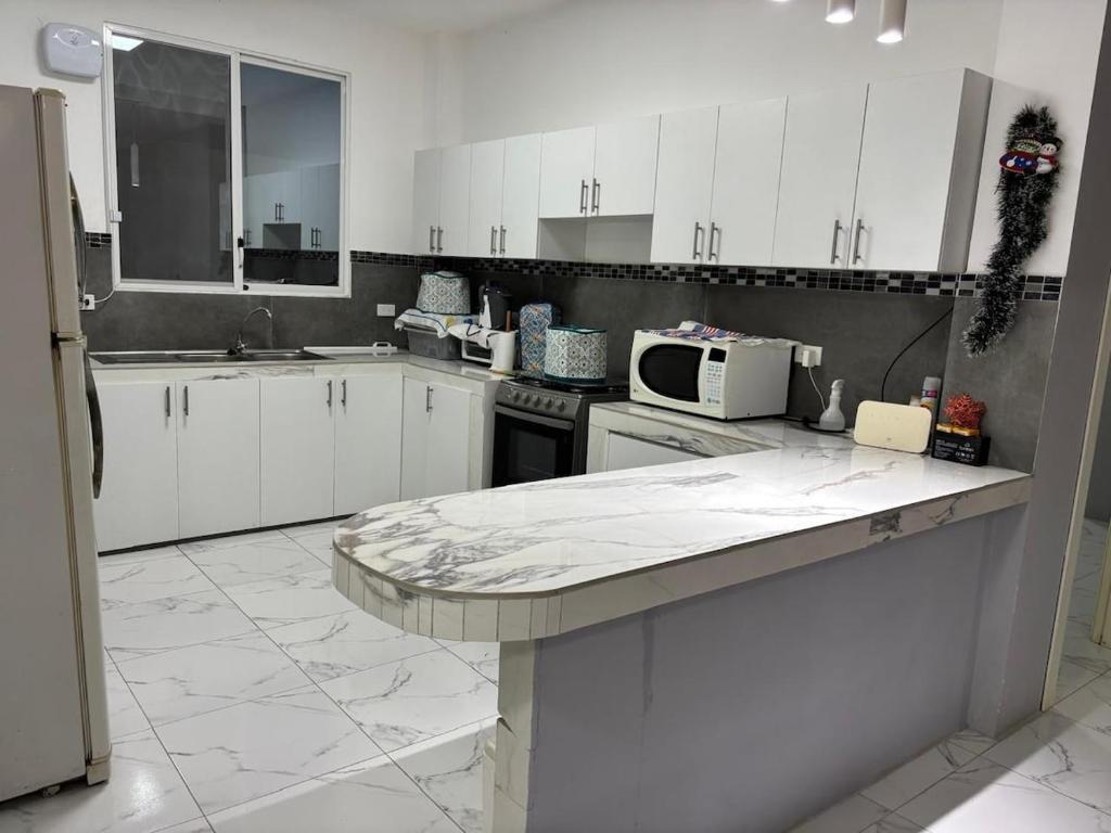 a kitchen with white cabinets and a marble counter top at Alojamiento en Ayangue in Santa Elena