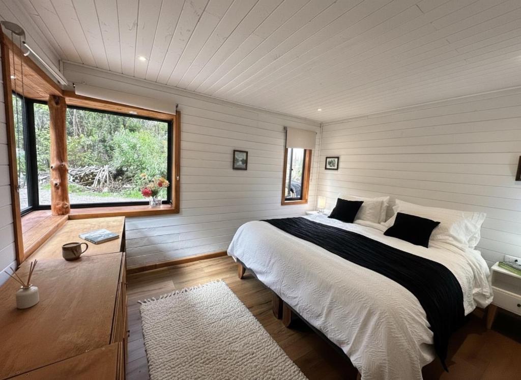 Un dormitorio con una cama grande y una ventana. en Cabañas Alto del Bosque, en Coñaripe