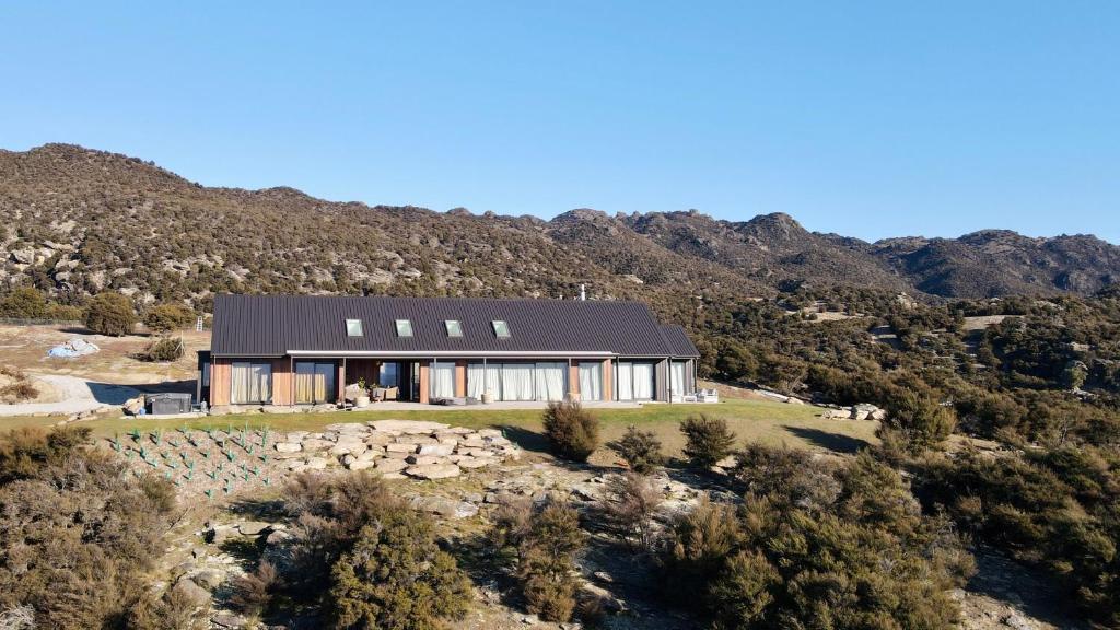 a house on a hill with mountains in the background at Bendigo Ridge - Where Activity is Relaxing in Cromwell