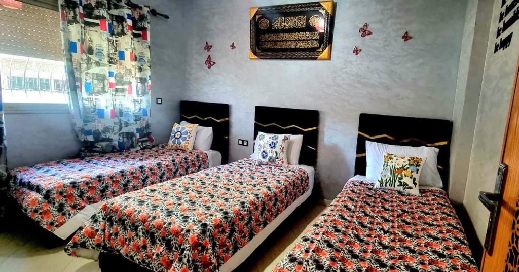 a bedroom with two beds and a wall at Apprt Ennakhil 2 in El Jadida