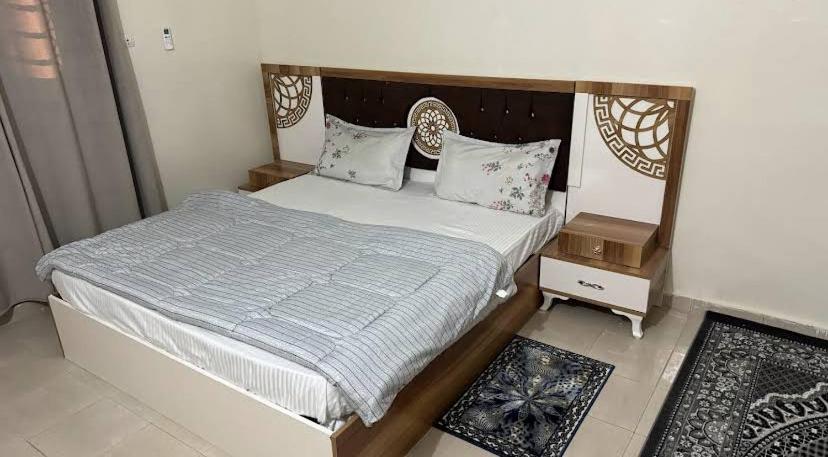 a bedroom with a large bed with a wooden headboard at Rose du Désert in Atar