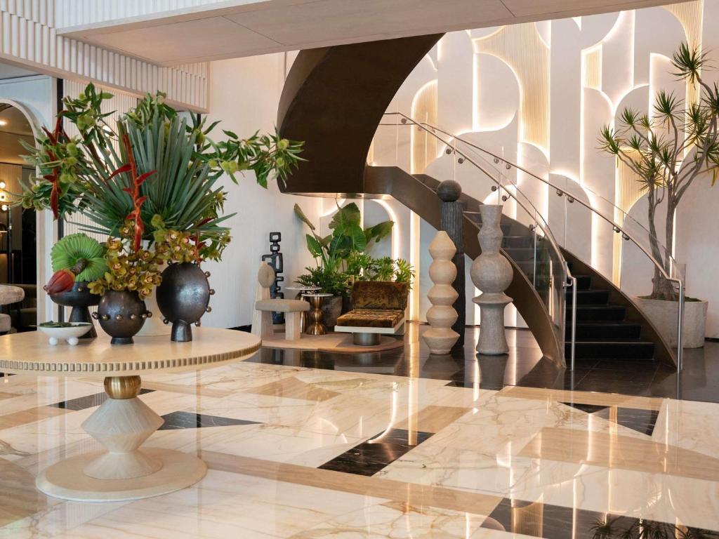 a lobby with a staircase with vases and plants at Hotel Sofitel Los Angeles at Beverly Hills in Los Angeles