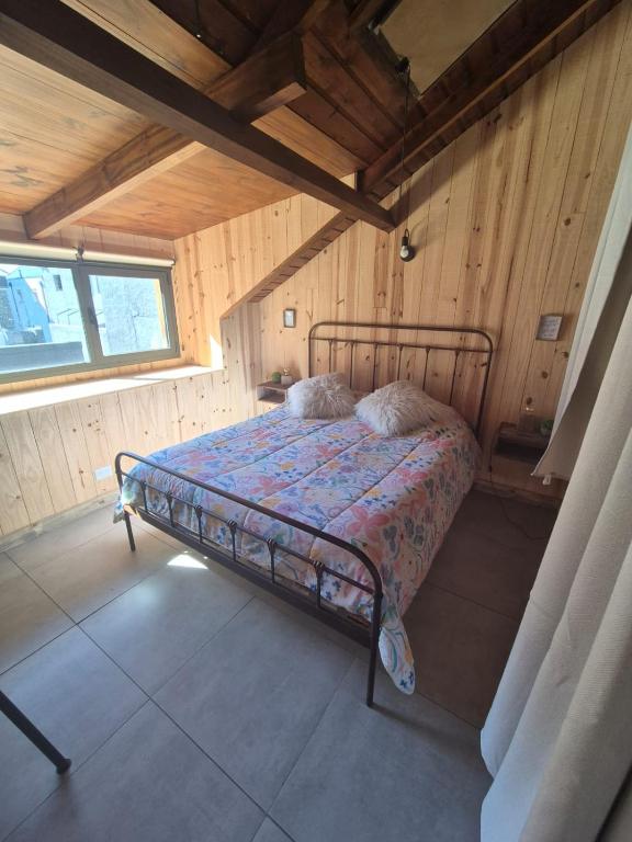 a bedroom with a bed in a room with wooden walls at Chapa atrás - SalePatagonia in San Martín de los Andes