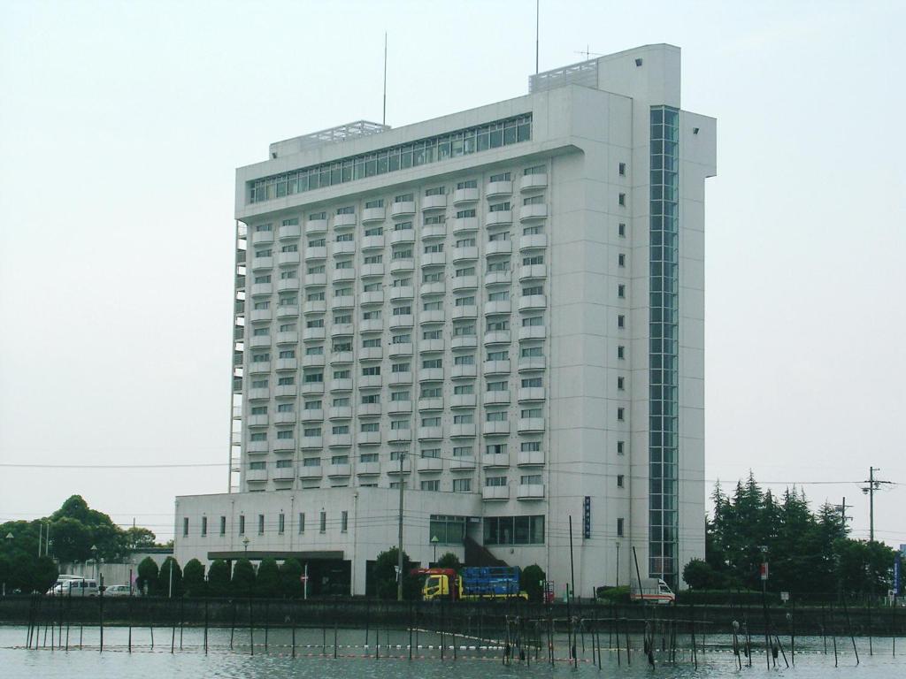 a large white building next to a body of water at Hotel Biwako Plaza in Moriyama