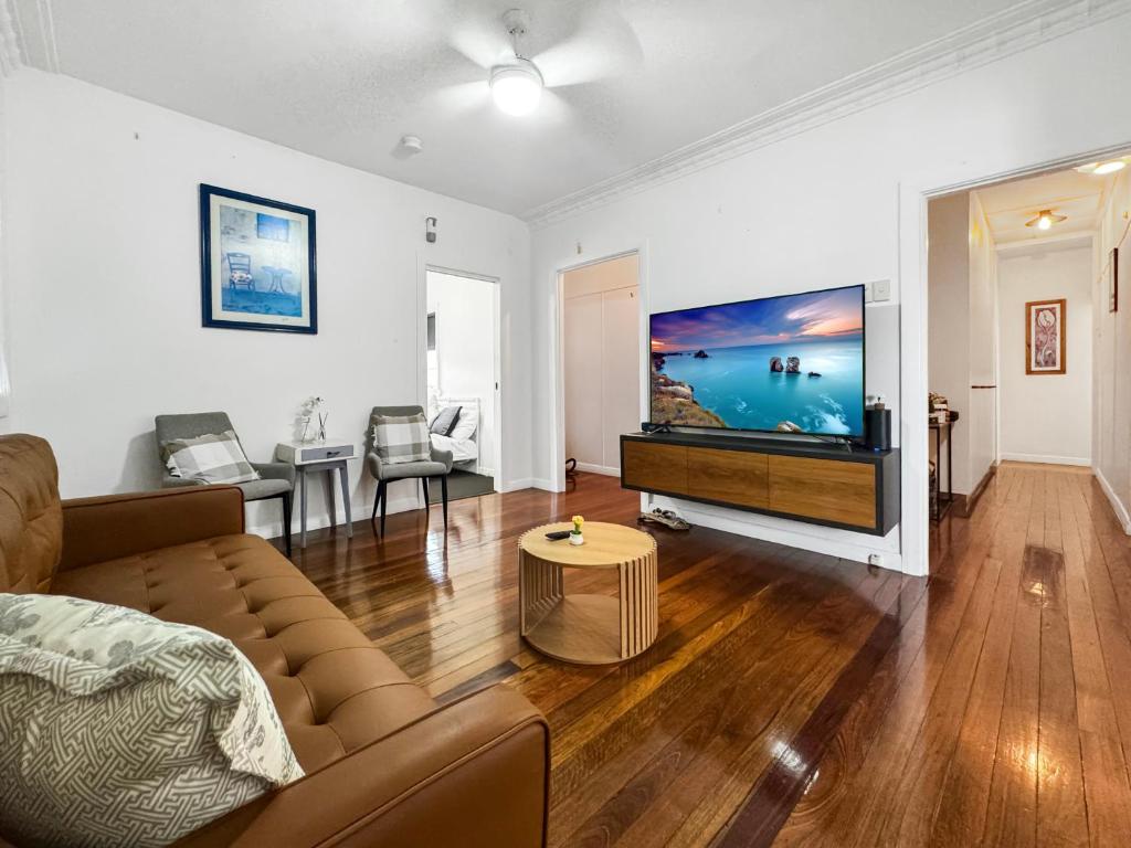 a living room with a couch and a flat screen tv at Cosy Cottage 4173 in Brisbane