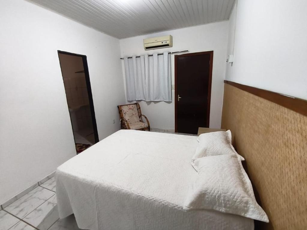 um quarto com uma cama branca e uma cadeira em Pousada Adventure em Chapada dos Guimarães