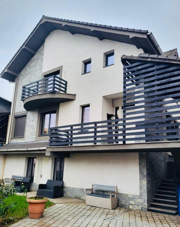 a large white building with a balcony and stairs at Promenada House Craiova in Craiova