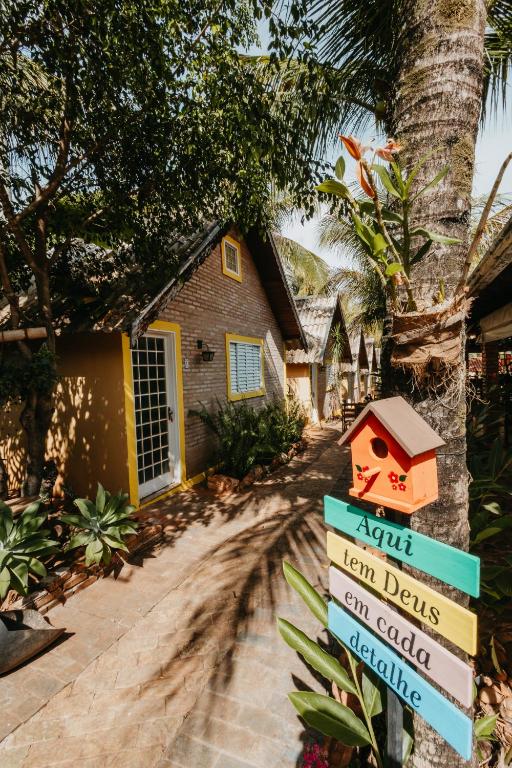 a sign in front of a house with a bird house at Pousada Chalés Jardim das Aguas in Olímpia