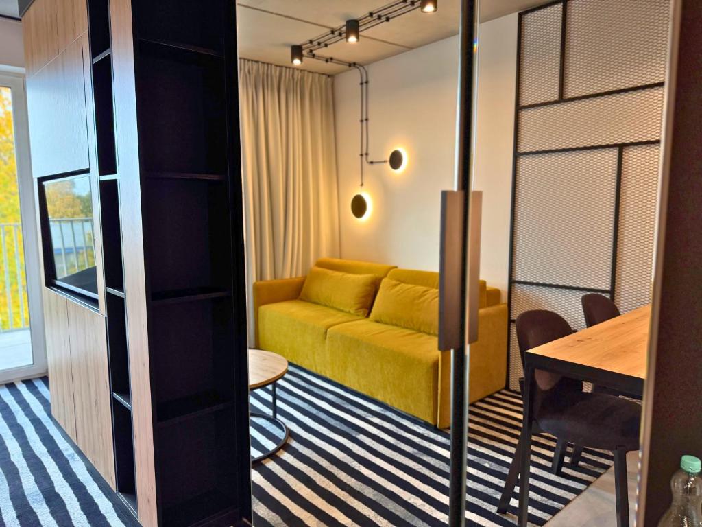 Green Port Spa&Wellness Rent Partners في كولوبرزيغ: غرفة معيشة مع أريكة صفراء وطاولة